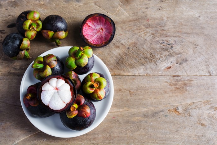 Mangosteens on a plate and wooden surface