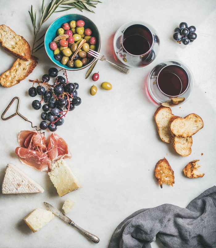 Charcuterie board with wine, cheese, ham, olives, and bread