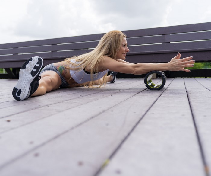 Woman doing a split stretch with a foam roller