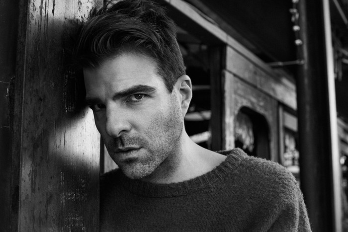 Zachary Quinto leaning against a wooden post