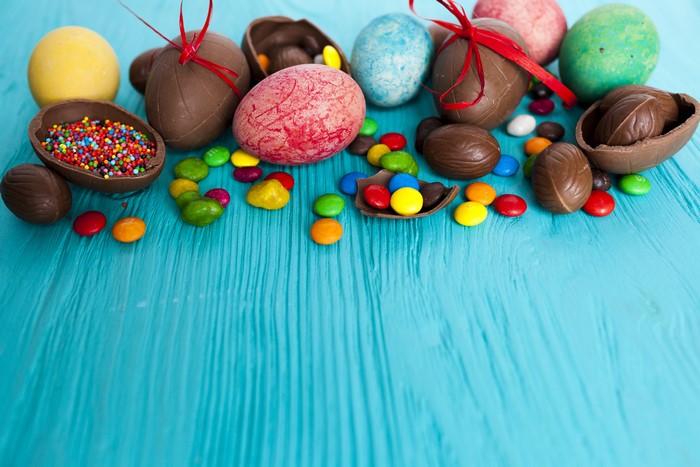 Easter chocolate eggs and candies on blue wooden background
