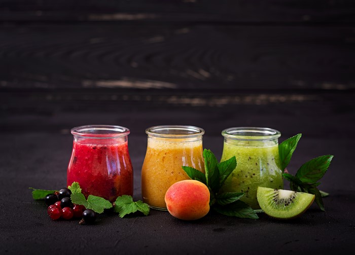 Three smoothies in jars with fruits and mint