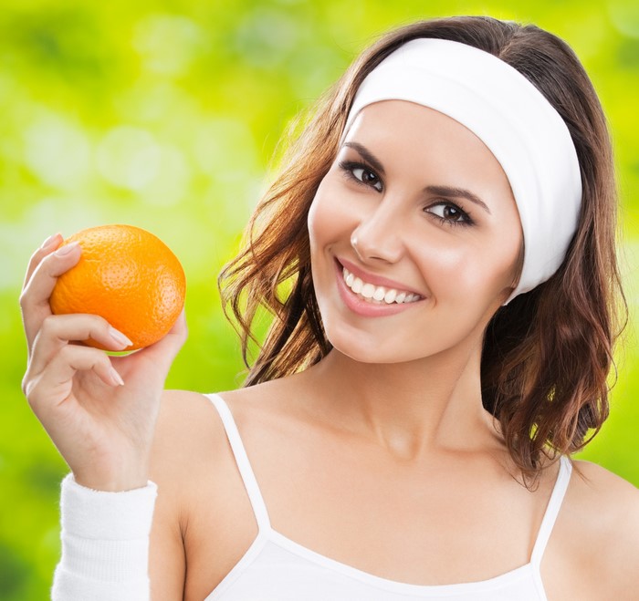 Woman in white headband holding an orange