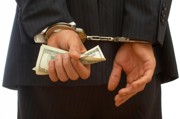 Man in handcuffs holding US dollars