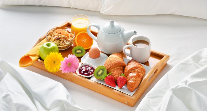 Breakfast tray with coffee, juice, croissants, and fruit