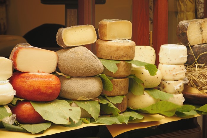 Many cheeses on display with foliage