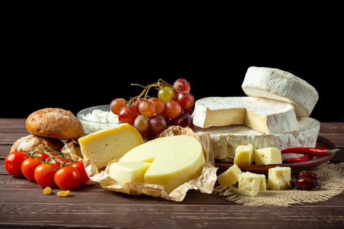 Cheese platter with bread, tomatoes, grapes, and chili peppers