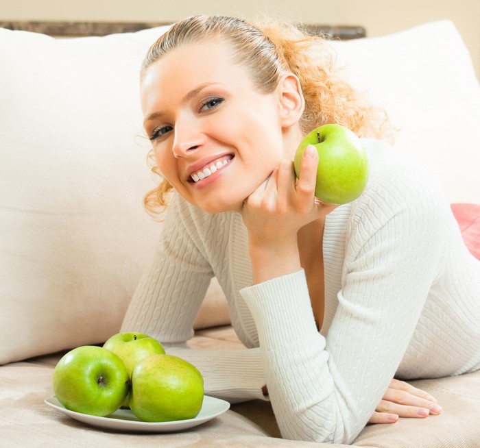 Blonde girl smiling with green apples