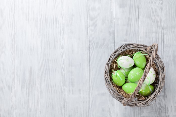 Easter eggs in a wicker basket on wood planks