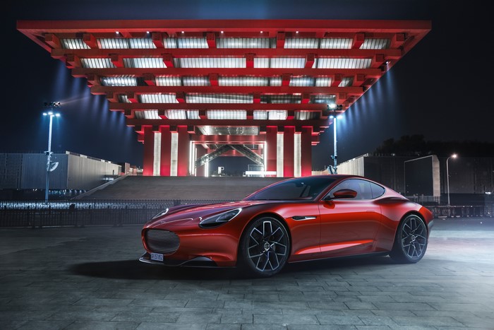Red sports car in front of a modern red building at night
