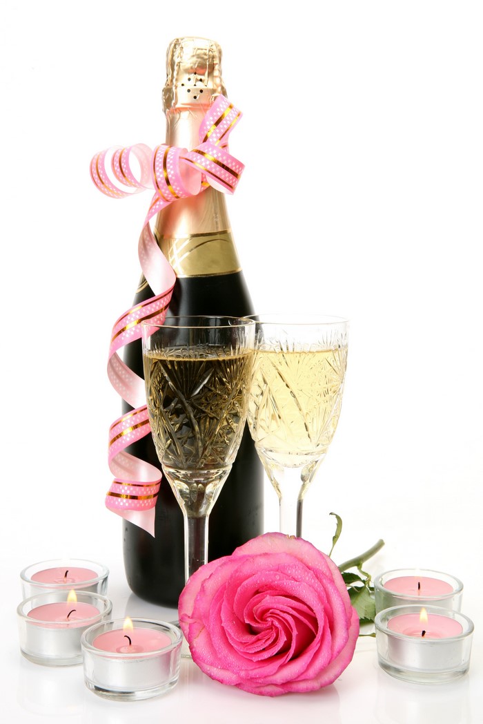 Champagne bottle with glasses, rose, and candles