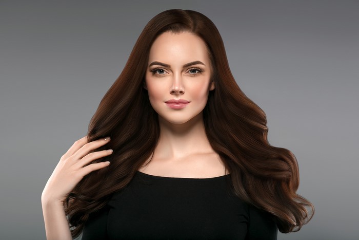 Brown haired woman with hand on hair