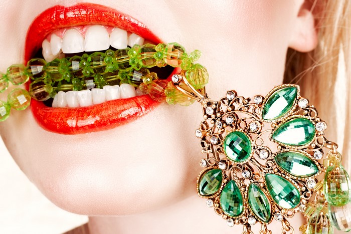 Woman with red lips biting green beads and jewelry