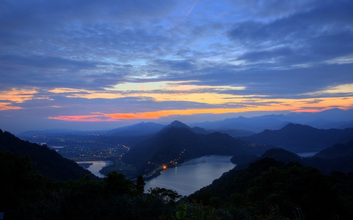 Mountain landscape with lake and city lights at dusk