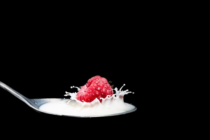 Raspberry splashing into milk on a spoon