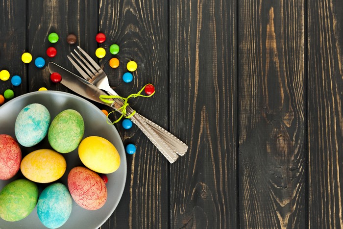 Easter eggs and candy on dark wood planks with cutlery