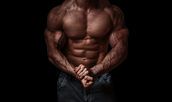 Bodybuilder flexing muscles on black background