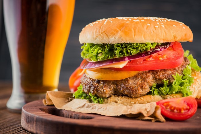 Hamburger with lettuce, tomato, onion, cheese, and beer