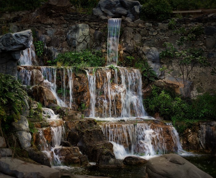 Artificial waterfalls cascading over rocks and greenery