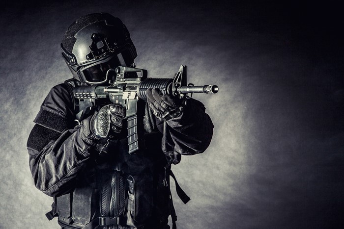 Soldier in tactical gear aiming an assault rifle