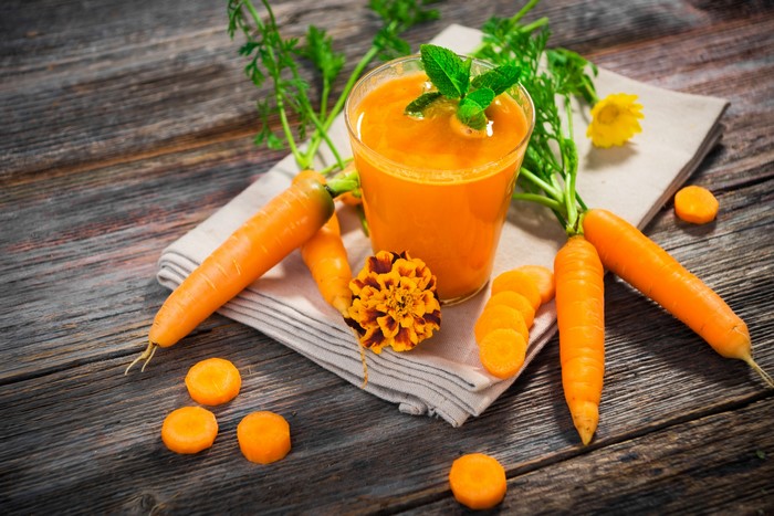 Carrot juice in a glass with fresh carrots