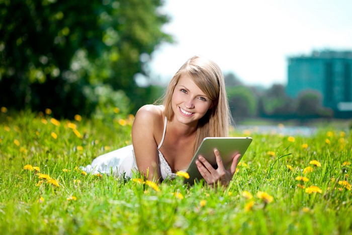 Blonde girl with tablet in field