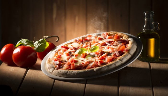 Pizza with tomatoes and olive oil on wood planks