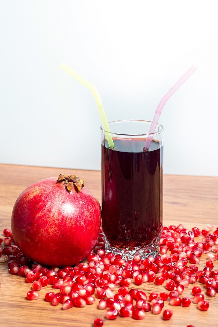 Pomegranate juice in a glass with a pomegranate and seeds