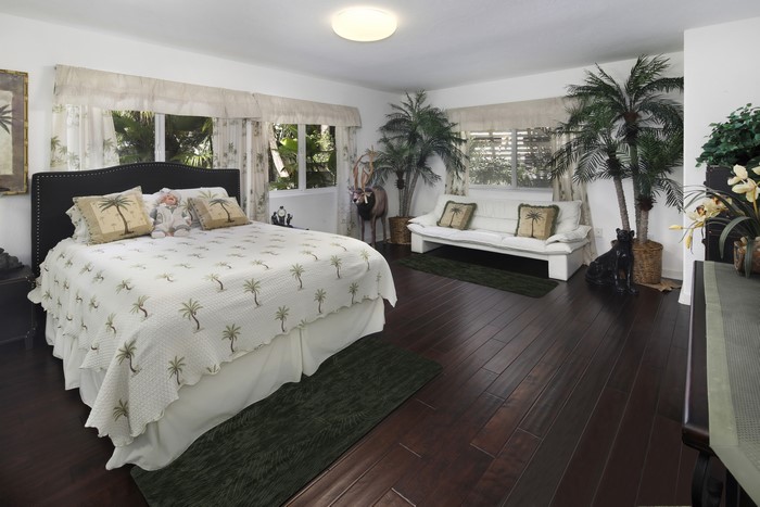Bedroom with bed, sofa, and palm tree decor