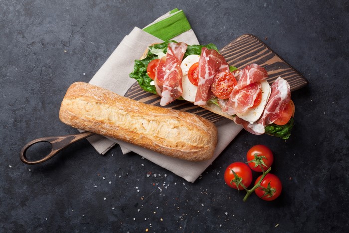 Sandwich with prosciutto, mozzarella, tomatoes, and lettuce on a baguette