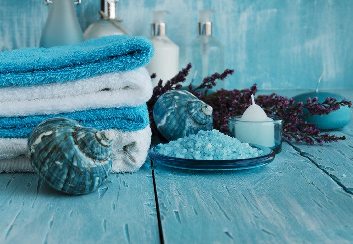 Spa towels, shells, salt, and candles on wood planks
