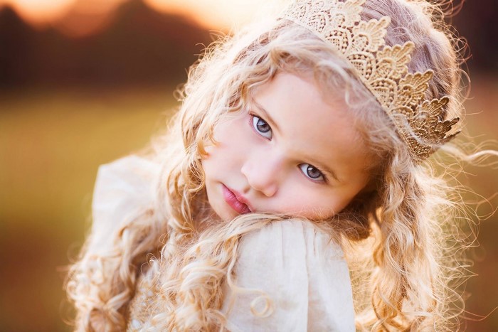 Young girl with blonde curly hair and a crown