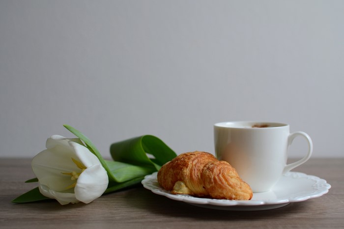 White tulip, croissant, and coffee cup