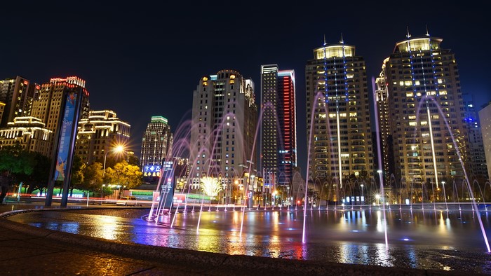 Night cityscape with illuminated buildings and fountains