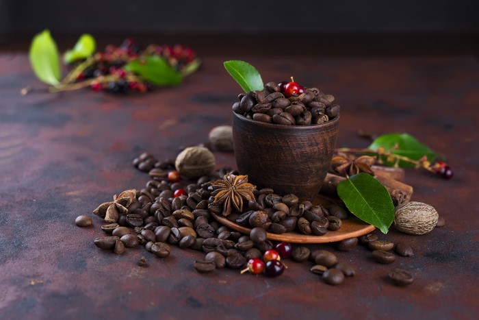 Coffee beans in a cup with spices and berries
