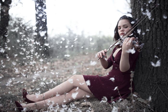 Woman playing violin with feathers falling