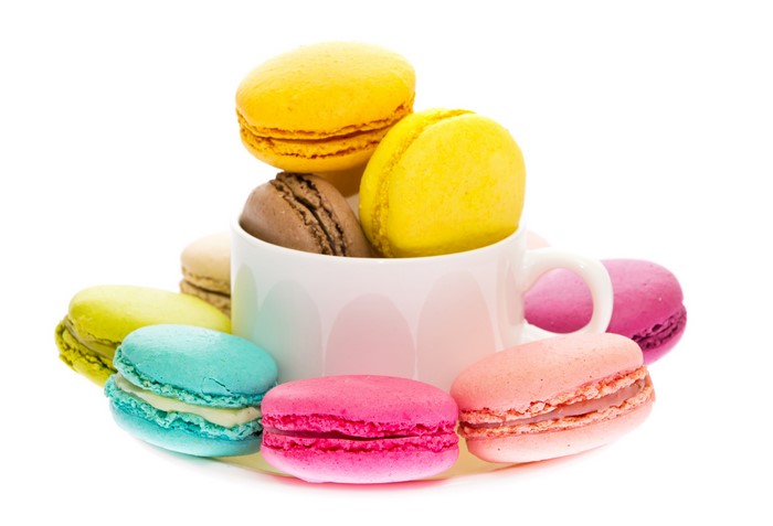 Colorful macarons in a white cup on a white background