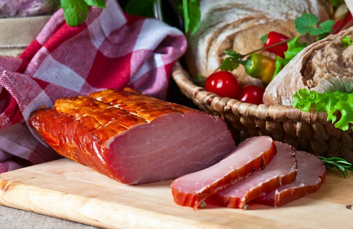 Smoked Ham on a Cutting Board with Bread and Vegetables
