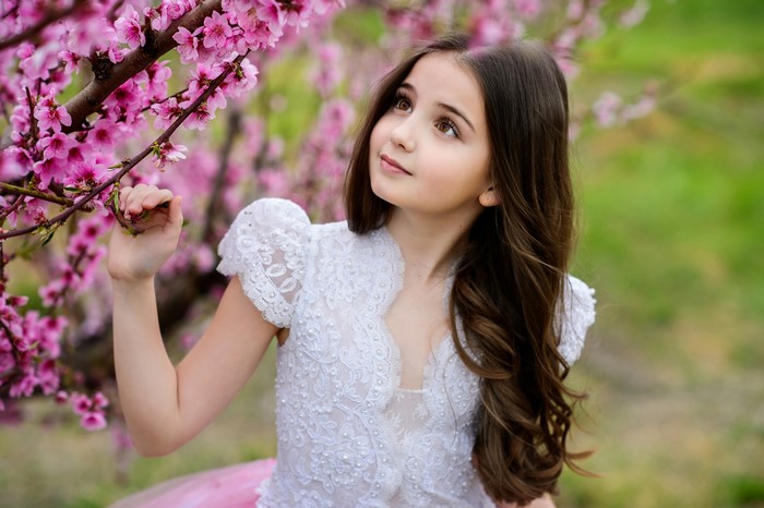 Girl in white dress near pink flowering tree