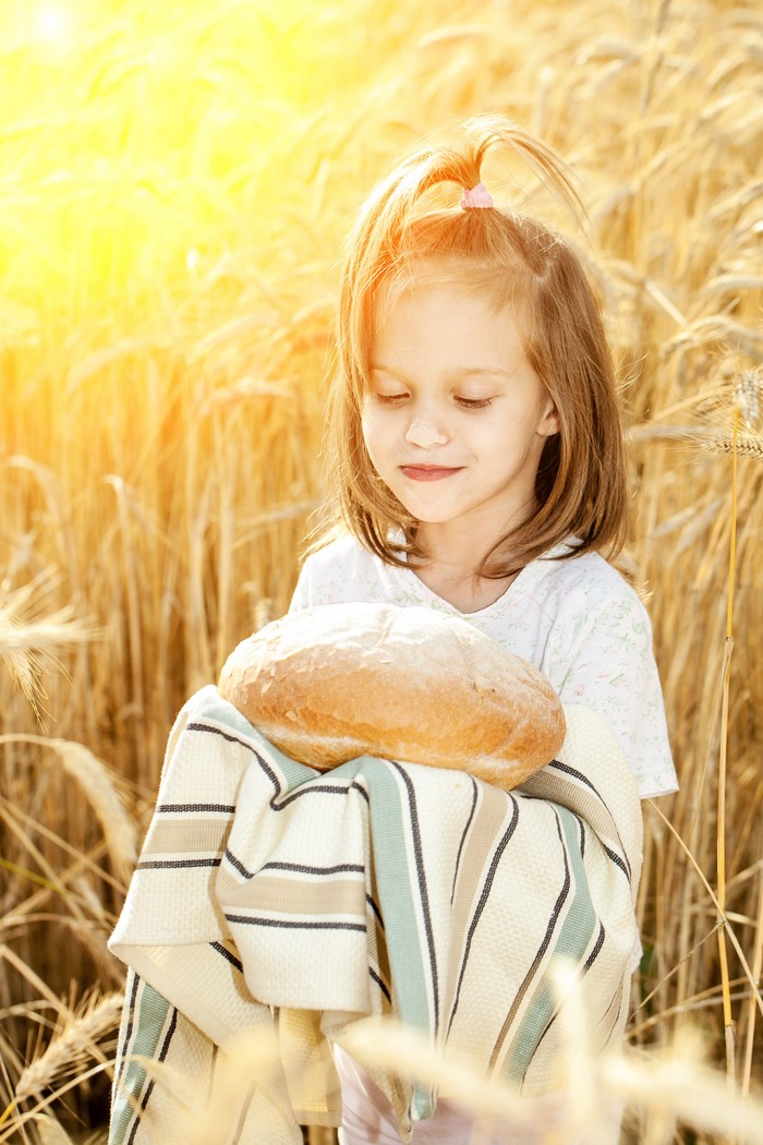 Girl holding bread in a wheat field