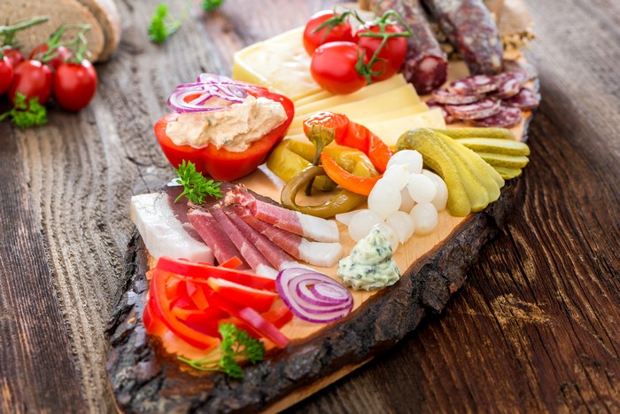 Charcuterie board with ham, cheese, vegetables, and pickles