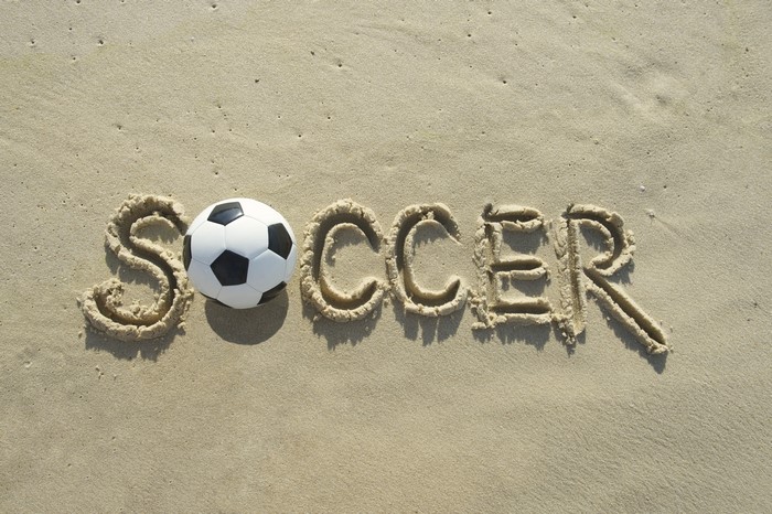 Soccer ball on sand with word Soccer written