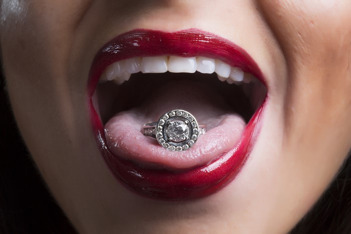 Woman with red lips and a ring on her tongue