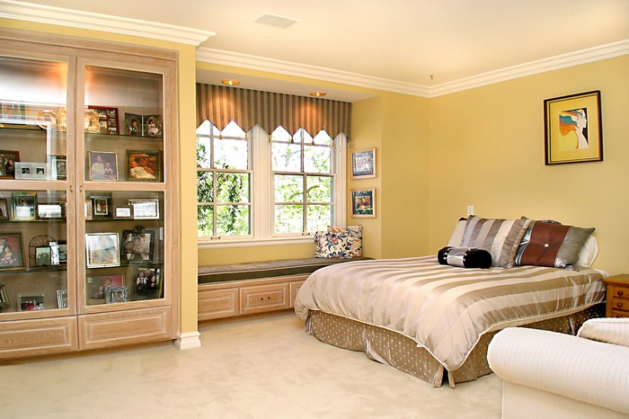 Bedroom with a bed, window seat, and display cabinet