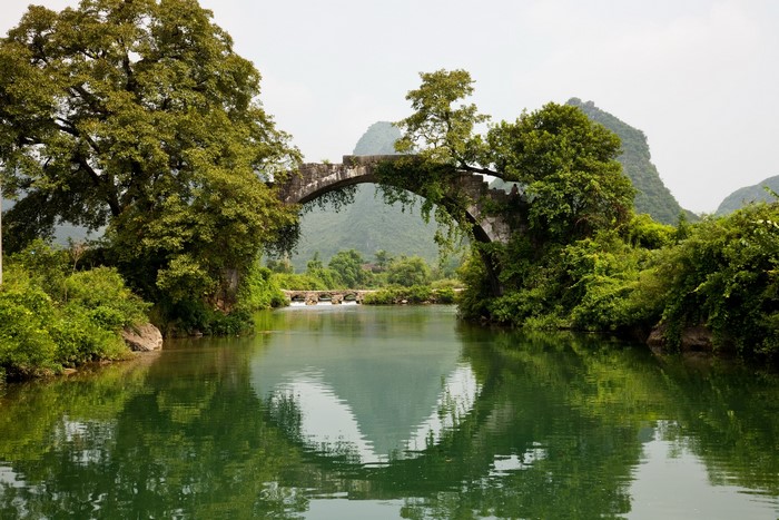 Stone arch bridge over a river with lush trees