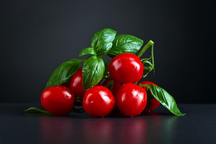 Tomatoes with basil on a gray background