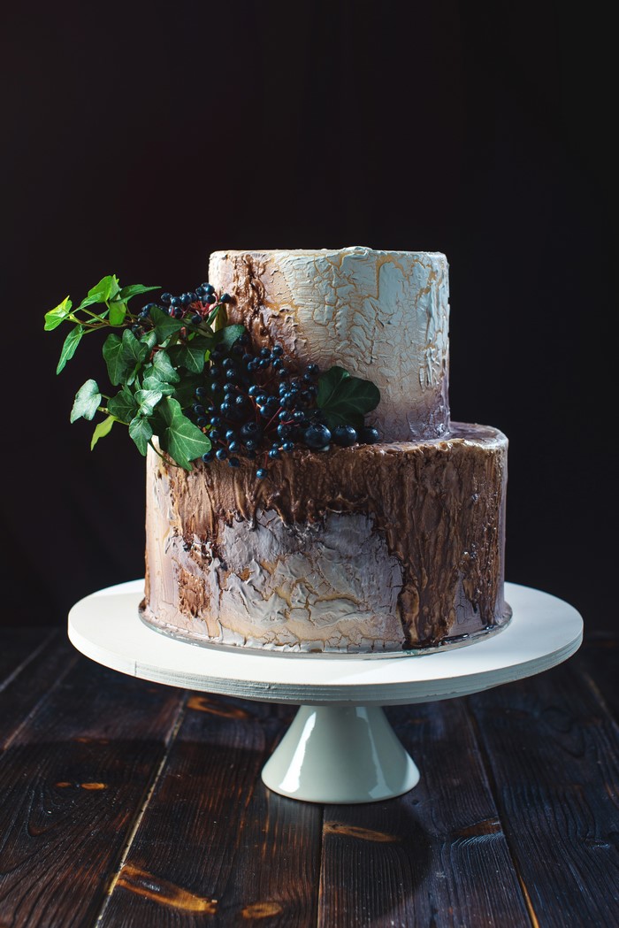 Two-tiered cake with berries and ivy