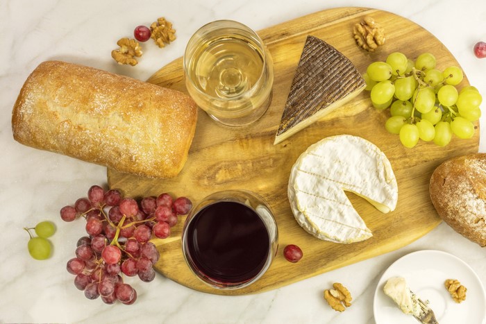 Cheese, Bread, Grapes, Nuts, and Wine on a Cutting Board