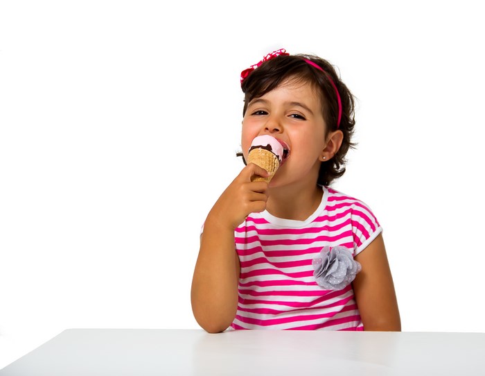 Little girl eating ice cream on white background