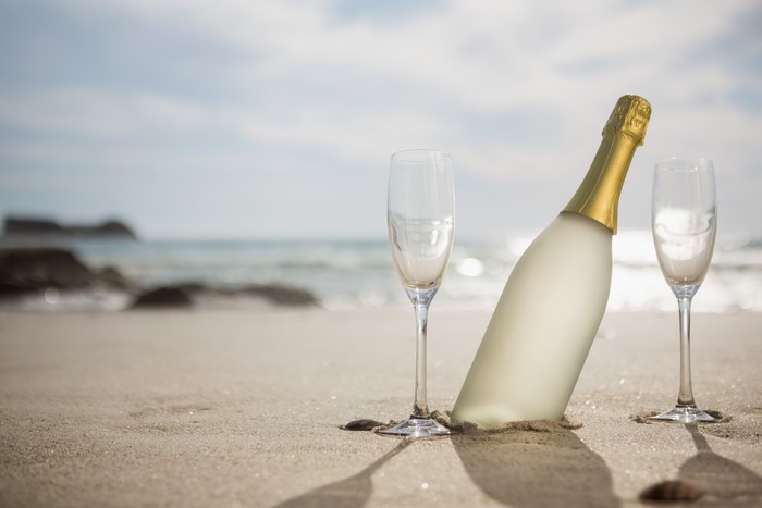 Champagne bottle and glasses on a sandy beach